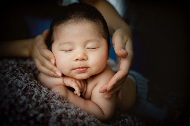 baby with parents hands near the face