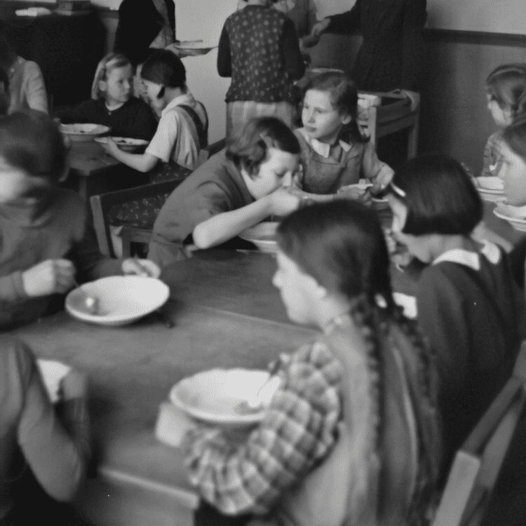 black and white photo of children eating in old-fashioned times.