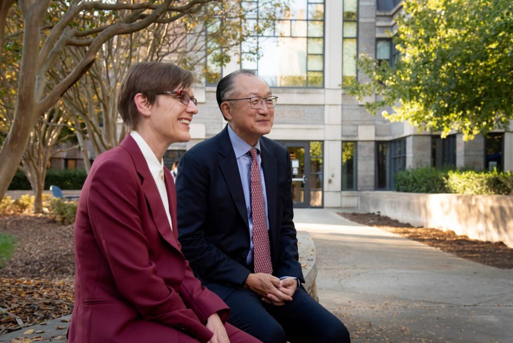 Dean Kelley and Dr. Kim sitting on wall, Sanford building in background